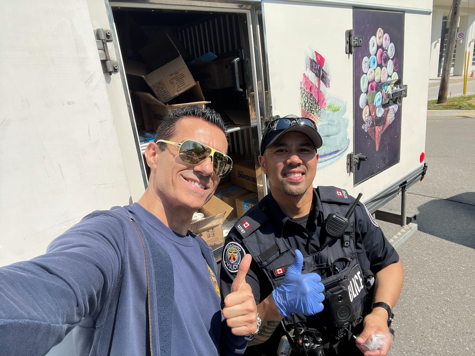 Sinan Erdemir giving a thumbs up with a Toronto police officer at a neighbourhood event