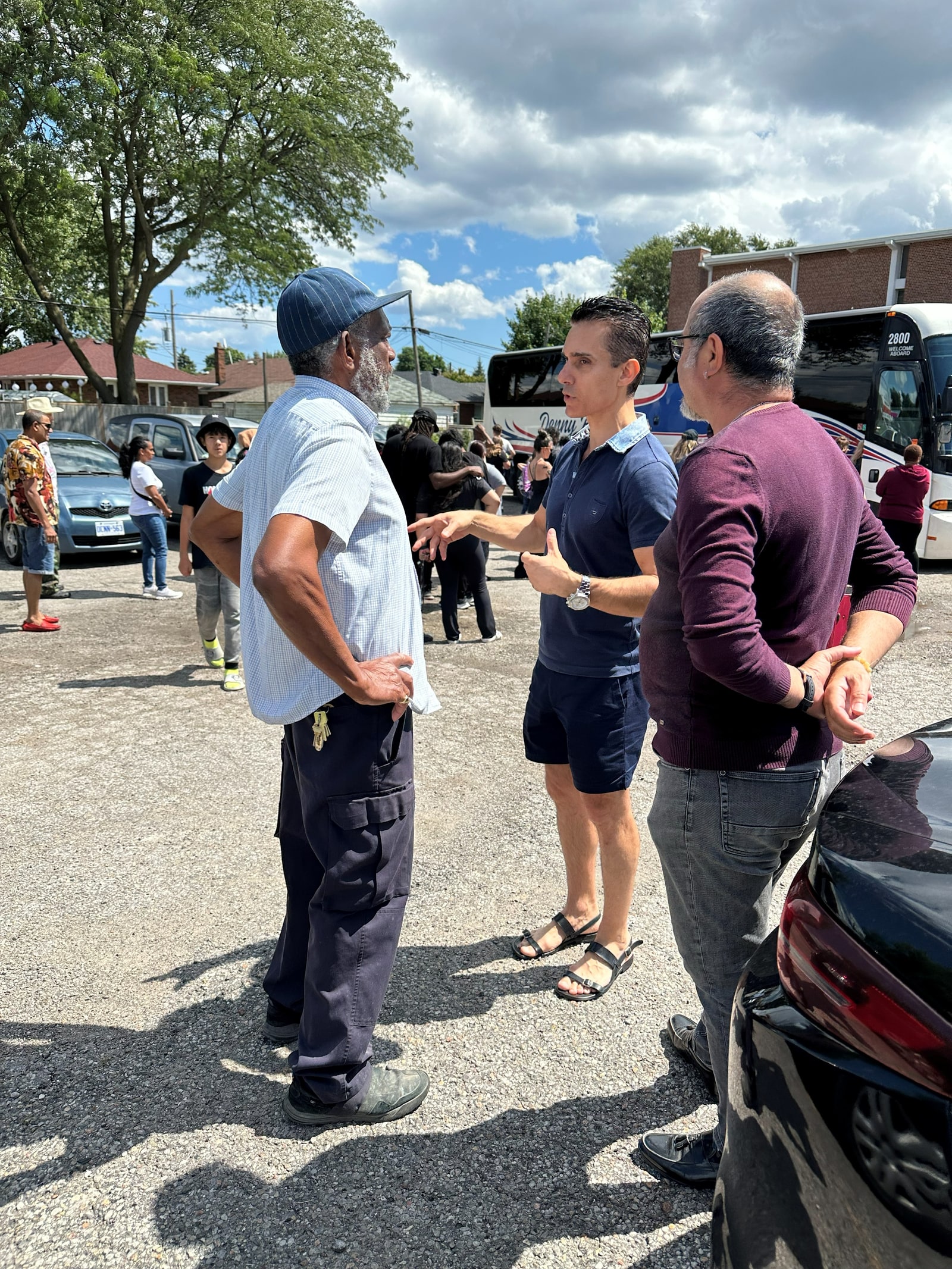 Sinan Erdemir talking with neighbours in a parking lot at a community outing