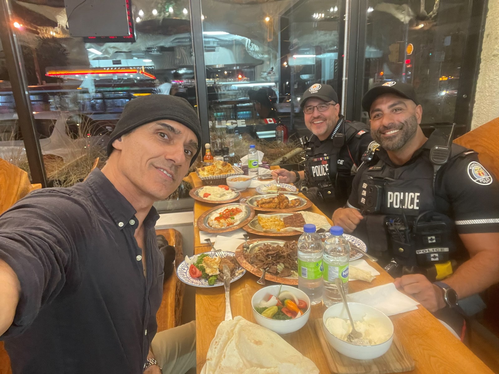 Sinan Erdemir sharing a meal with two Toronto police officers at a local restaurant